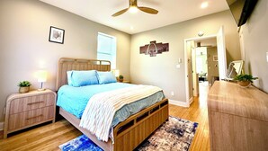A bedroom with a bed, nightstands, a ceiling fan, a TV, and a door leading to another room. - Luxury & Views That Sleeps 11 - In The Heart of all things St Louis (St. Louis)
