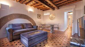 A cozy living area with a sofa, ottoman, and a glass-top dining table with chairs. - Scala Suite (Rome)