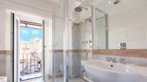 A modern bathroom with a glass-enclosed shower, a large sink, and a mirror. - Scala Suite (Rome)