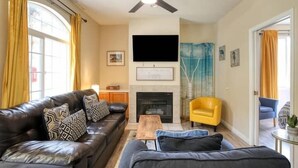 Una sala de estar con sofá, una mesa de centro, chimenea y televisor.
