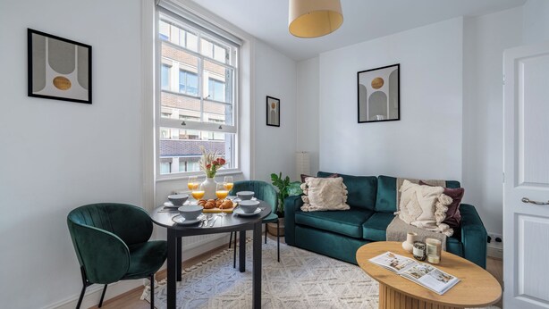 Un salon moderne avec une table à manger, un canapé vert et une table basse.