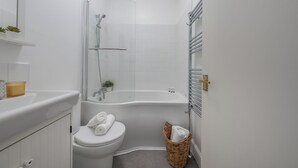 Une salle de bain de taille réduite, équipée de toilettes, d’une baignoire et d’une douche.