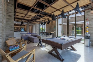 Un espacio interior moderno con mesa de billar, mesa de fútbol y zona de estar.