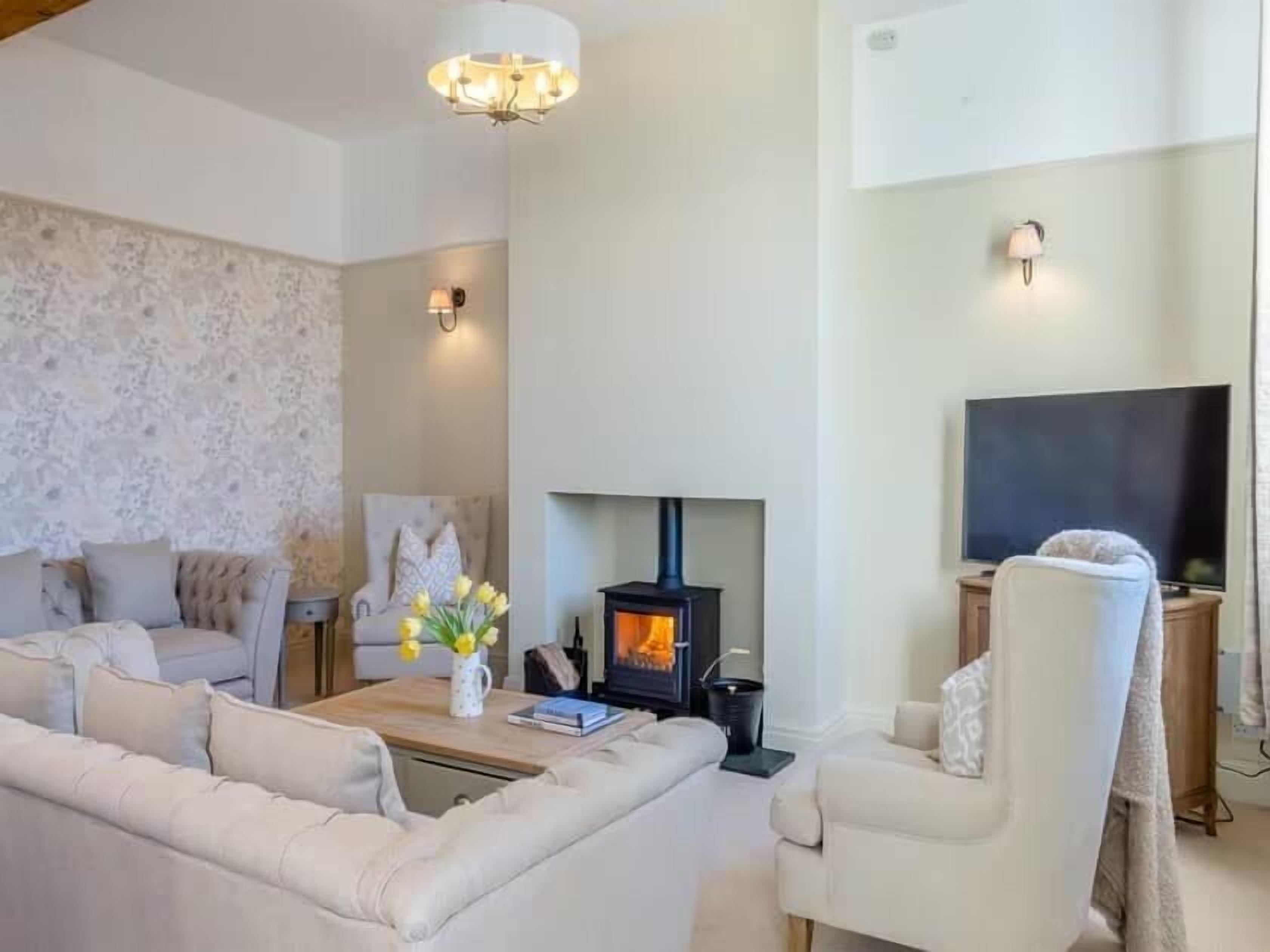 A cozy living room with a fireplace, a sofa, a chair, and a television.