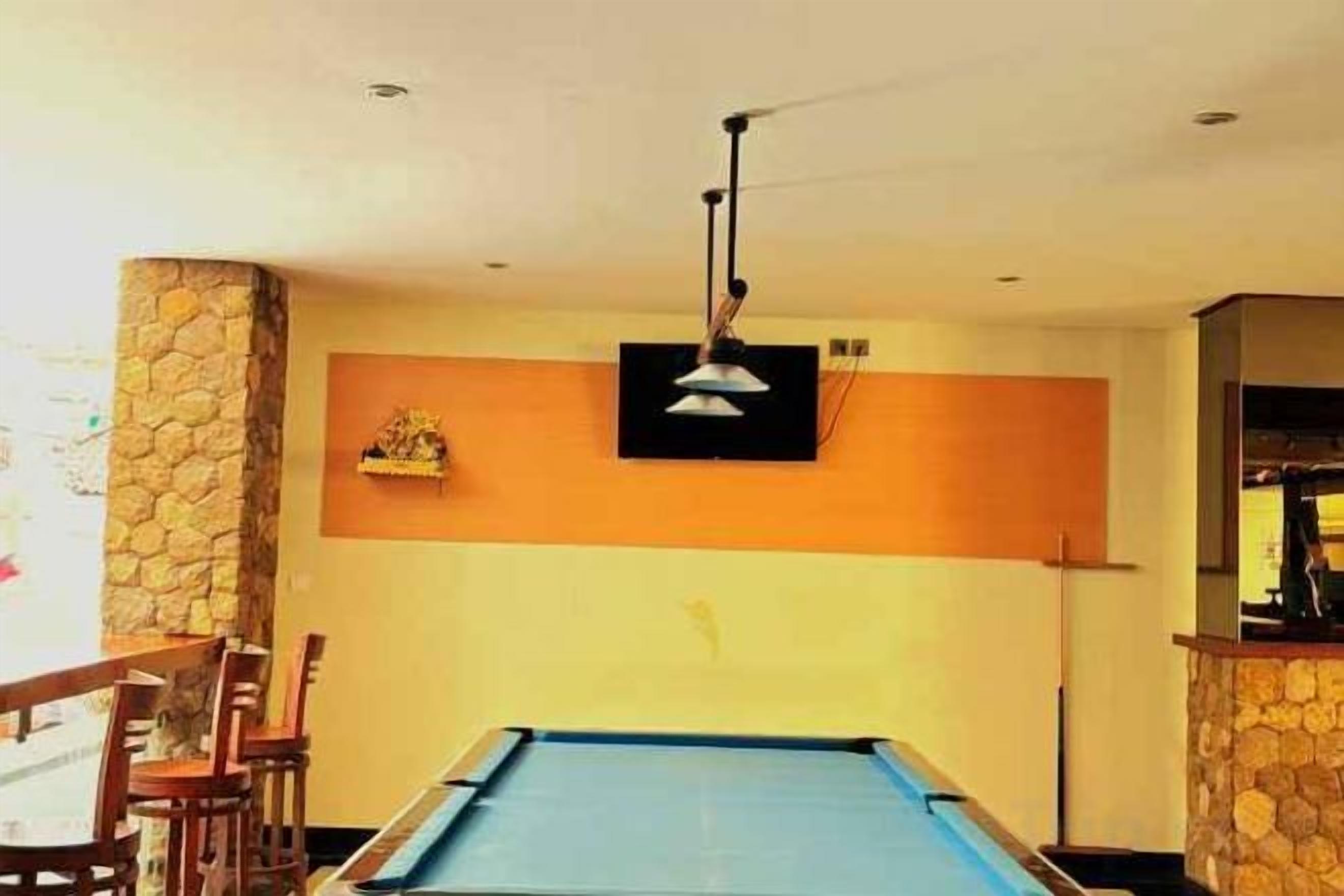 A pool table in a room with stone walls and a hanging light fixture.