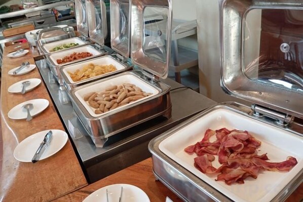 A buffet with various food options in metal containers. - Kuta Town Houses (Bali)