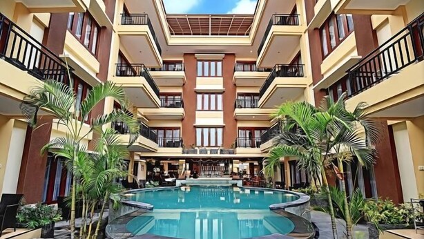 A multi-level hotel with a central pool, balconies, and tropical plants. - Kuta Town Houses (Bali)