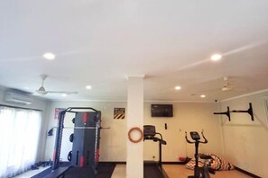 A gym with a weightlifting station, a stationary bike, and a treadmill. - Kuta Town Houses (Bali)