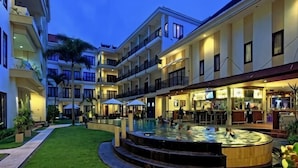 A hotel courtyard with a pool, outdoor seating, and multiple balconies. - Kuta Town Houses (Bali)