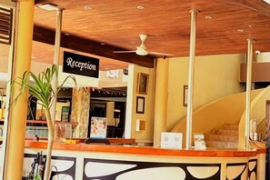 A reception area with a wooden ceiling, a reception desk, and a sign labeled 'Reception.' - Kuta Town Houses (Bali)