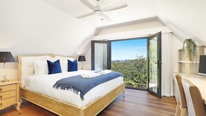 A bedroom with a bed, bedside tables, a ceiling fan, and a view through an open door. - Goolara – luxurious two-storey escape with ensuite bedrooms, sauna and countryside views (Burrawang)