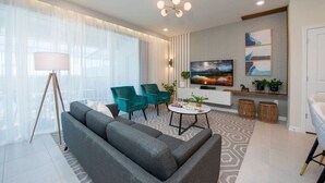 Un salon moderne comprenant un canapé, deux fauteuils, une table basse et un téléviseur.