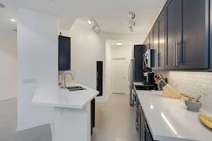 Una cocina moderna con encimeras blancas, armarios oscuros y un microondas integrado.