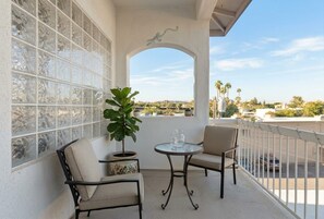 Ein Balkon mit zwei Stühlen, einem Tisch und einem Blumentopf.