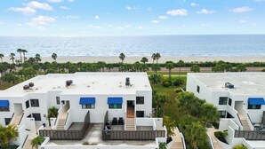 Un hôtel moderne aux façades blanches et aux auvents bleus, doté de nombreux balcons et offrant une vue sur la plage et l’océan.