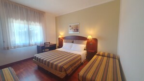 A hotel room with a double bed, two bedside tables, a desk, a chair, and a window with curtains. - Agriturismo Gli Ulivi (Predappio)