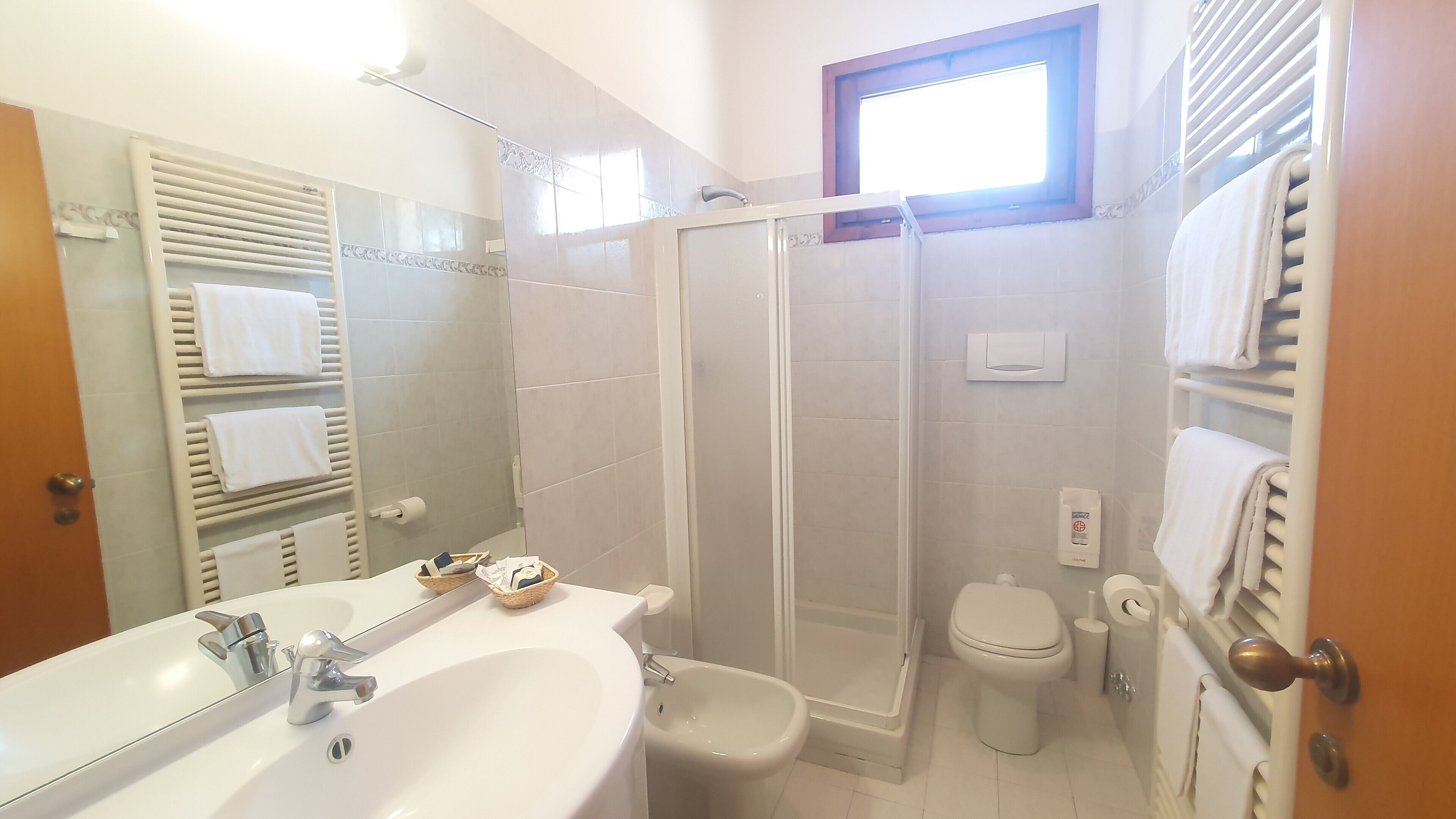 Een badkamer met een wastafel, spiegel, douche, toilet en handdoekrek.