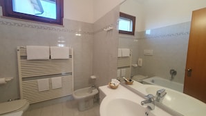 A modern bathroom with a bathtub, a sink, and a toilet. There are multiple towel racks and a mirror above the sink. - Agriturismo Gli Ulivi (Predappio)