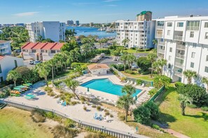 Un resort con piscina, palmeras y un puerto deportivo al fondo.