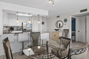 Una cocina moderna con gabinetes blancos, electrodomésticos de acero inoxidable e iluminación colgante.