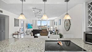 A modern kitchen with a granite countertop, stainless steel appliances, and pendant lighting. - Dolphin Point #406a (Destin)