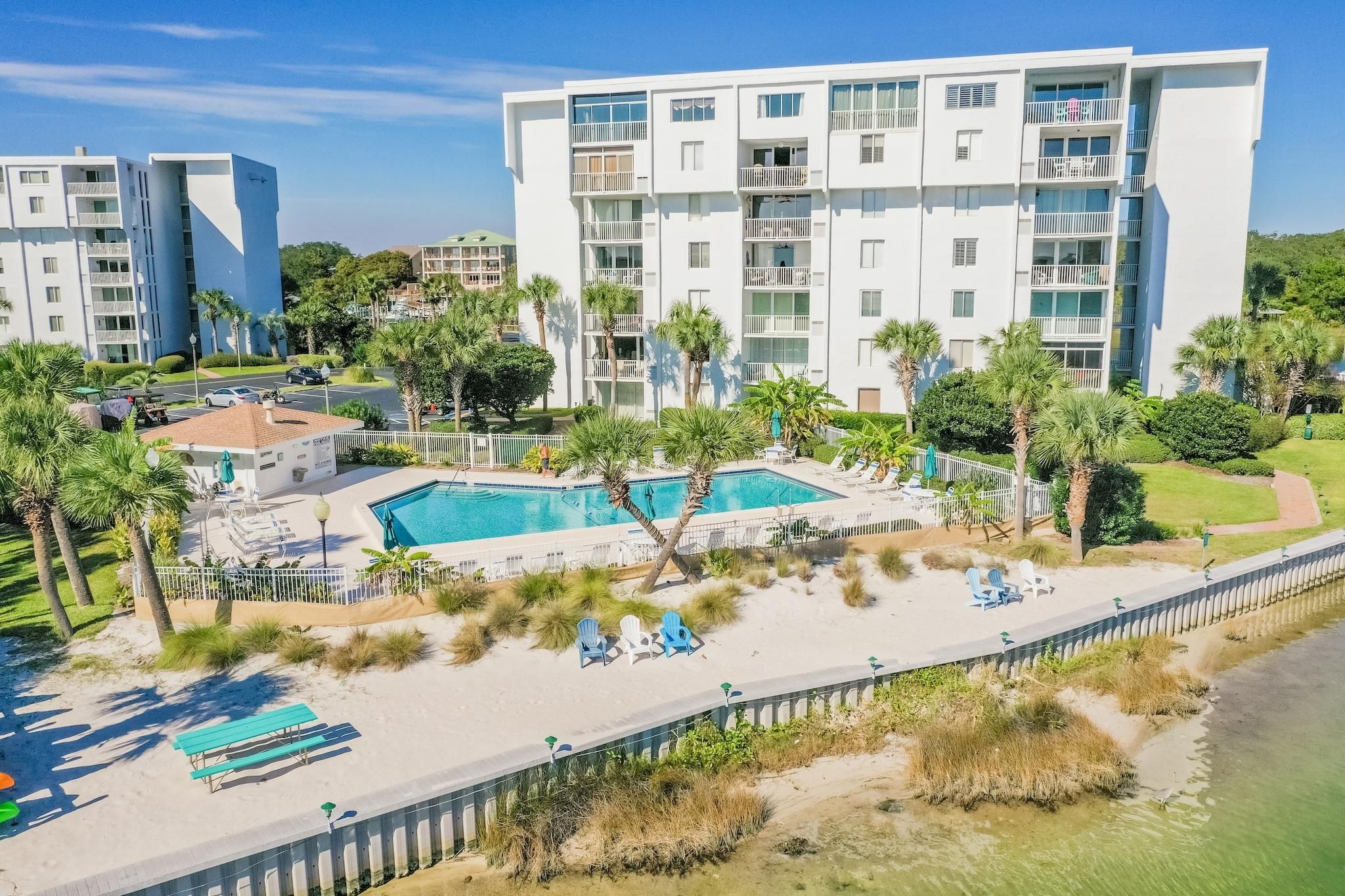 A modern hotel with a pool, palm trees, and beach chairs.