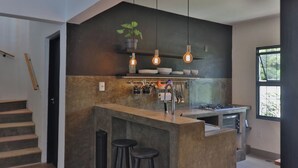A modern kitchen with a central island, hanging pendant lights, and a window providing natural light.
