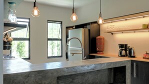 A modern kitchen with a large island, pendant lights, a coffee maker, and a water dispenser.