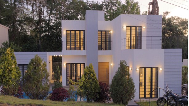 A modern two-story house with a driveway, a motorcycle, and a well-maintained garden.