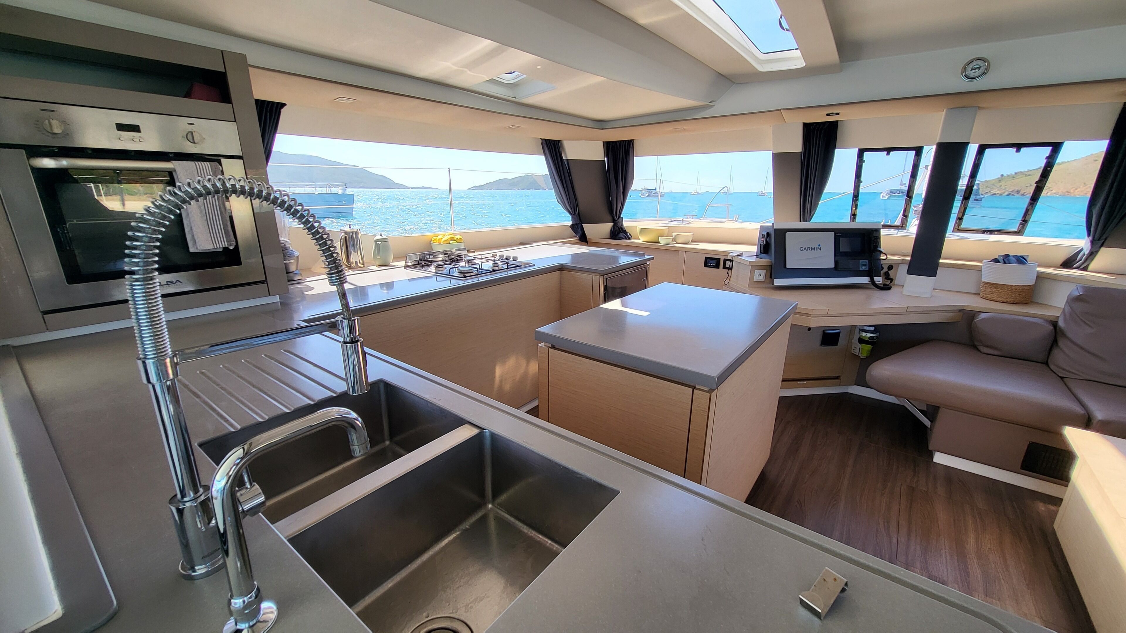 A compact galley with a stainless steel sink, a compact stove, and a small galley table.