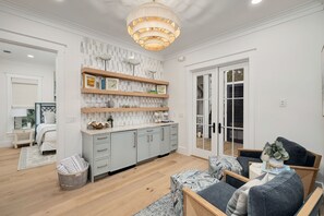 A modern living room with a sofa, a dining area with a table and chairs, and a kitchen with light-colored cabinets and a patterned backsplash. - Blue Water Haven|Private Heated Pool|Golf Cart|Newly Remodeled (Santa Rosa Beach)