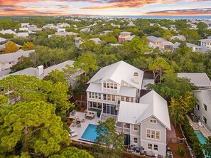 A residential area with houses, a large house with a swimming pool, and a view of the ocean at sunset. - Blue Water Haven|Private Heated Pool|Golf Cart|Newly Remodeled (Santa Rosa Beach)