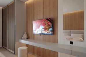 A modern hotel room with a mounted TV displaying various streaming services, a wooden panel wall, and a neatly made bed. - Azura Exclusive Villa (Acharavi)