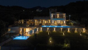 Ein modernes, zweistöckiges Haus mit Swimmingpool, Sitzgelegenheiten im Freien und gut beleuchteten Wegen.