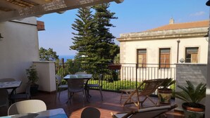 An outdoor patio with a table, chairs, and potted plants. - Anemone is an independent apartment consisting of an equipped kitchen-living room with a single sofa bed, a double bedroom overlooking the main square and the sea, and a bathroom made of handmade ceramic, equipped with a washing machine. The accommodatio (SANTO STEFANO DI CAMASTRA - ME)
