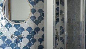 A bathroom with a sink, mirror, and shower. - Anemone is an independent apartment consisting of an equipped kitchen-living room with a single sofa bed, a double bedroom overlooking the main square and the sea, and a bathroom made of handmade ceramic, equipped with a washing machine. The accommodatio (SANTO STEFANO DI CAMASTRA - ME)
