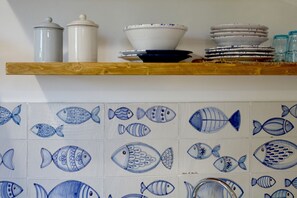 Een keukenschap met witte en blauwe keramieken borden, een witte pan en een blauwe kom.