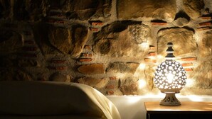A room with a stone wall, a bed, and a table with a decorative lamp. - Anemone is an independent apartment consisting of an equipped kitchen-living room with a single sofa bed, a double bedroom overlooking the main square and the sea, and a bathroom made of handmade ceramic, equipped with a washing machine. The accommodatio (SANTO STEFANO DI CAMASTRA - ME)