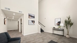 A modern living room with a grey sofa, a console table with a lamp, and a potted plant. - The Landmark 2 King Beds, Garage & Fireplace (Fort Collins)