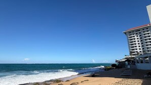 Una playa con un hotel al fondo.