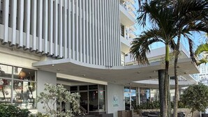 Un edificio moderno con fachada vertical, zona de estar al aire libre y un letrero que dice 'Best Coffee of Puerto Rico'.