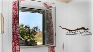 Une pièce avec une fenêtre, un porte-manteau mural et une plante en pot.