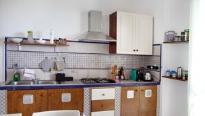 Une cuisine de taille réduite, dotée d’une cuisinière à gaz, de meubles blancs et d’un crédence carrelée aux motifs bleus et blancs.