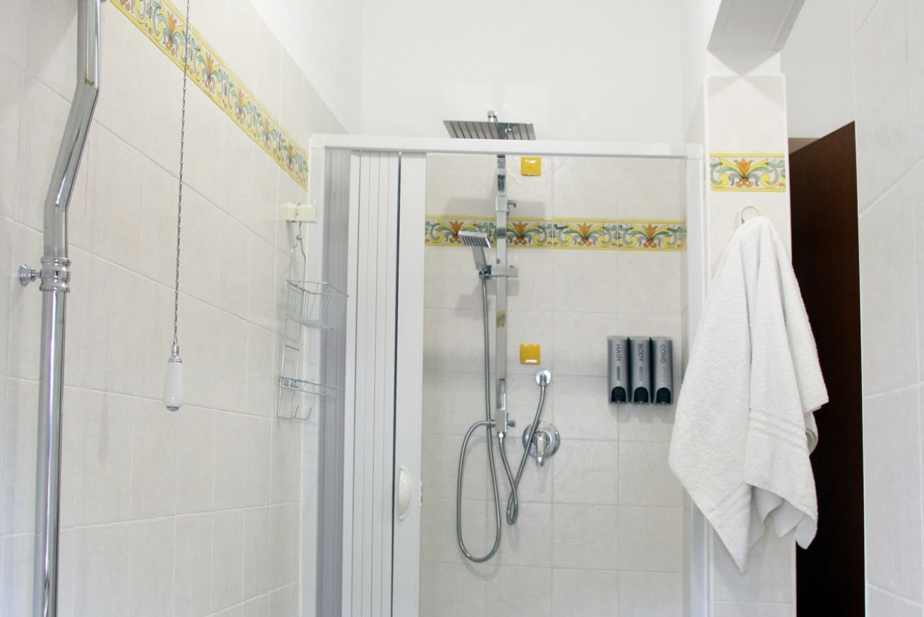 Un’area doccia con porta in vetro, soffione e portasciugamani con un asciugamano.
