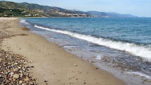 Une plage de galets avec une vue sur des collines lointaines.