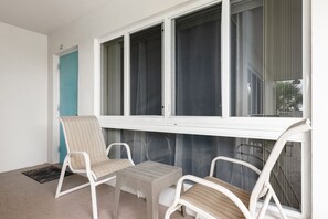 A balcony with white wicker chairs, a small table, and a view of the outside through large windows. - Pompano 3225 20A (Pompano Beach)
