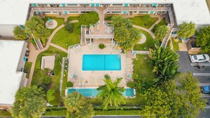 An aerial view of a hotel with a central swimming pool, multiple balconies, and surrounding greenery. - Pompano 3225 20A (Pompano Beach)
