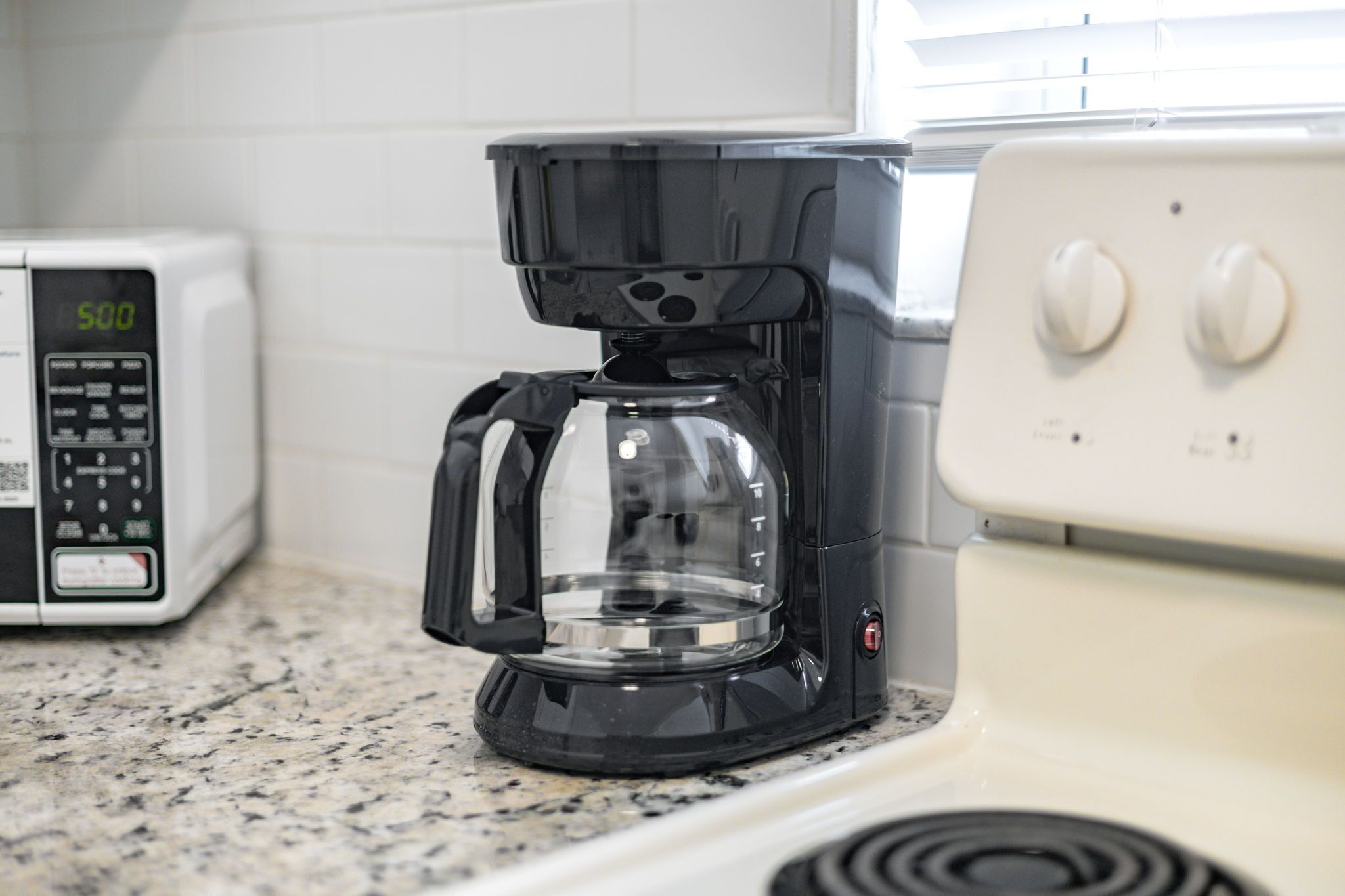 Een keuken met een koffiezetapparaat, magnetron en fornuis.