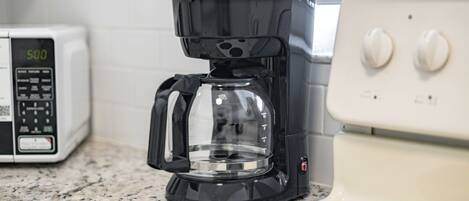Een keuken met een koffiezetapparaat, magnetron en fornuis.