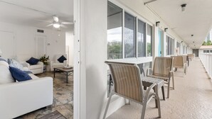 A clean, modern hotel room with a white sofa, a small table, and a ceiling fan. - Pompano 3225 20A (Pompano Beach)